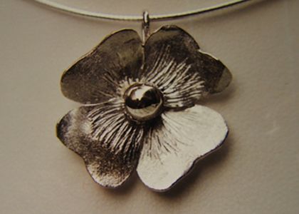 Zilveren urnhanger in de vorm van een bloem met ashouder als bolvormig bloemenhart.